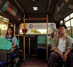 two people sitting on a bus with their luggage