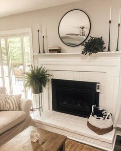 a living room filled with furniture and a fire place in front of a mirror on the wall