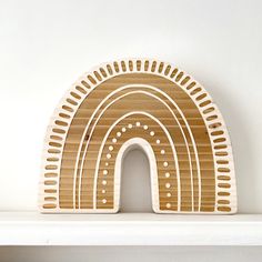 a white shelf with a wooden sculpture on it's side and a rainbow in the middle