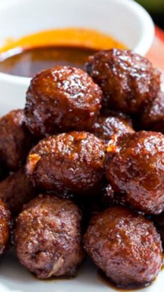 some meatballs are sitting on a plate with dipping sauce in the bowl behind them