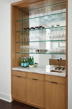 a kitchen with glass shelves filled with wine glasses