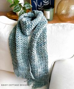 a blue and white scarf sitting on top of a couch next to a potted plant