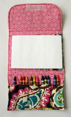 a pink case with crayons and a white piece of paper