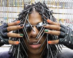 a woman with metal nails on her face and hands, holding up the top of her head