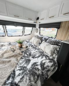 a bed in the back of a camper with black and white bedspread