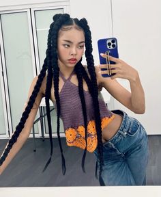 a woman with long braids taking a selfie in front of her cell phone