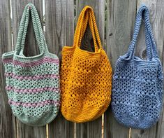 three crocheted purses hanging on a wooden fence, one in blue and the other in yellow