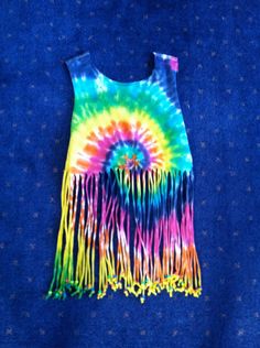 a tie - dyed shirt with fringes on it is laying on a blue surface