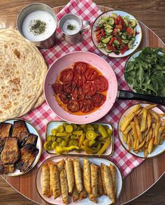 a table topped with plates filled with different types of food next to flat breads