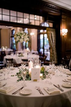 the table is set with white linens and place settings