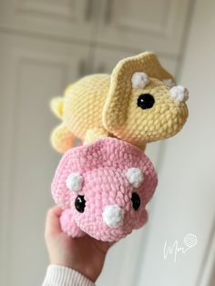 two crocheted stuffed animals are held up in the air by a person's hand