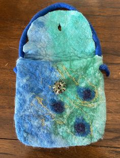 a blue and green purse sitting on top of a wooden table