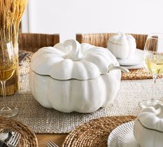 a white pumpkin sitting on top of a table next to some wine glasses and silverware