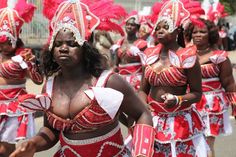 a group of women in red and white costumes walking down the street with their arms around each other