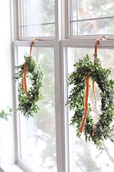 two wreaths hanging from the side of a window