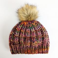 a multicolored knit hat with a pom - pom on top