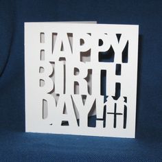 a white card with the words happy birthday written in black on it, sitting on a blue background