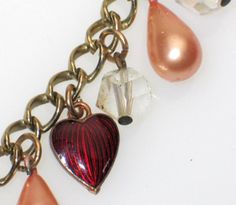 "Antique Vintage Crystal Heart & Guilloche Red Enamel Charm Bracelet 7 3/8\" Dainty gold finish link bracelet features 1920's - 1950's charms, which include: a large faceted crystal heart, 2 embossed copper purse / handbag shape charms with hand painted rose enamel hearts, 4 peach color faux pearl drops, 2 red guilloche enamel hearts, and 4 dangling Aurora Borealis crystal beads. Sweet and feminine! Don't miss this chance at a one-of-a-kind piece! Unmarked Measures approximately 7 3/8\" long Vintage Bracelets With Heart Beads For Gift, Red Metal Heart Bracelet As Gift, Handmade Charm Bracelet For Valentine's Day, Valentine's Day Heart Bracelet With Charms For Jewelry Making, Heart Bracelet With Lobster Clasp For Valentine's Day, Valentine's Day Metal Charm Bracelet With Heart Beads, Vintage Adjustable Heart Bracelet For Valentine's Day, Red Charm Bracelet With Heart Charm As Gift, Red Metal Heart Bracelet Gift