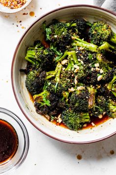 a bowl filled with broccoli and sauce next to some other dishes on the table