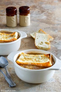 two white bowls filled with food next to bread