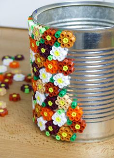 a tin can filled with lots of colorful beaded flowers on top of a wooden table