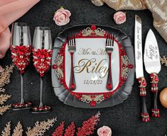 the table is set with red and gold place settings, silverware, and flowers