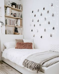 a bedroom with white walls and lots of bookshelves on the wall above the bed