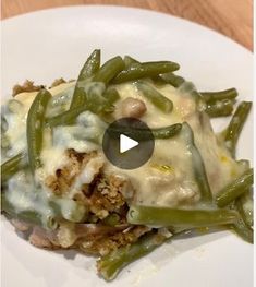 a white plate topped with green beans covered in cheese