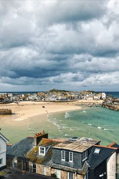 the beach is next to some houses and buildings under a cloudy sky with white clouds