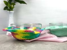 two bowls are sitting next to each other on a table with a pink napkin and green plant in the background