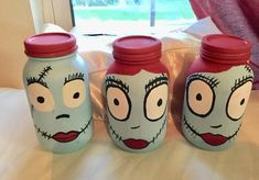 three jars with faces painted on them sitting on a bed next to a window in a bedroom