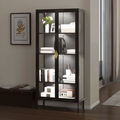 a black bookcase with glass doors is in the corner of a room next to a window