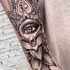 a woman's arm with an eye and flower tattoo on the left side of her body