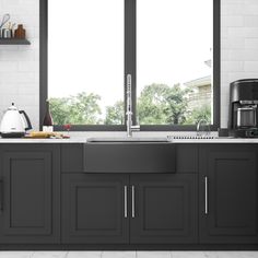 a kitchen with black cabinets and white tile flooring that has open windows to the outside