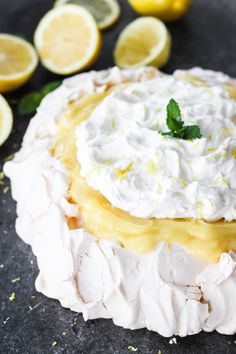 a lemon pie with whipped cream and limes around it on a black countertop