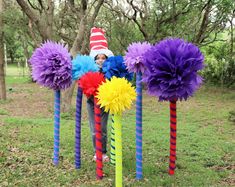 a child wearing a clown hat standing in front of colorful sticks with flowers on them