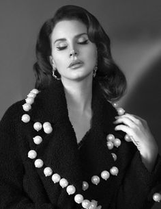 black and white photograph of a woman with pearls on her neck, wearing a coat