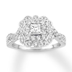 a white gold ring with diamonds on the sides and a square center stone surrounded by leaves