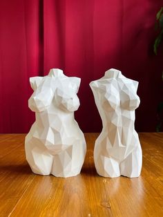 two white sculptures sitting on top of a wooden table