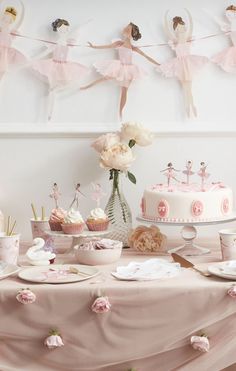 a table topped with cakes and cupcakes covered in pink frosted icing