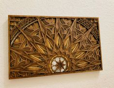 an intricately designed wooden wall hanging on the side of a white wall with a circular window