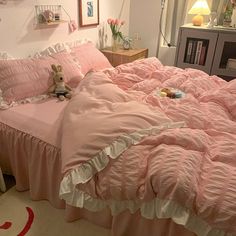 a pink bed with ruffled bedspread and pillows