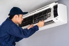 a man fixing an air conditioner on the wall