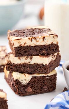 three chocolate brownies stacked on top of each other next to a glass of milk