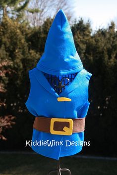 a blue hooded costume on top of a metal stand in front of some bushes and trees