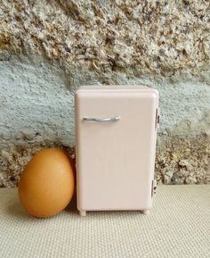 an egg sitting next to a refrigerator in front of a stone wall