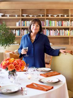 a woman holding a wine glass in front of a table with plates and glasses on it