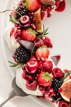 a white plate topped with fruit and whipped cream covered in berries, kiwis