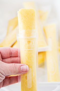 a person holding a tube of yellow sugar in front of some pieces of food on a plate