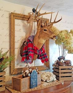 a deer head mounted to the side of a wall next to wooden crates filled with flowers